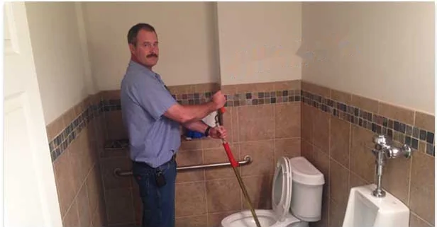 Plumber clearing a clogged toilet in an Annapolis commercial restroom