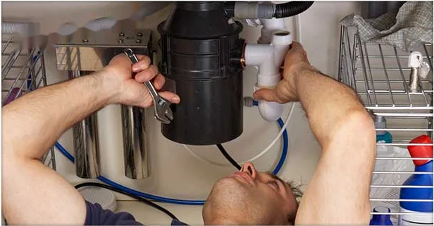 Plumber installing a garbage disposal under a kitchen sink