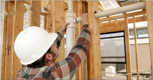 Plumber running vent and supply piping through new construction framing