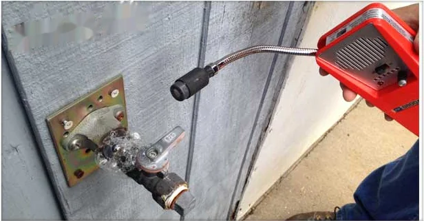 Technician testing an exterior gas line connection at the meter