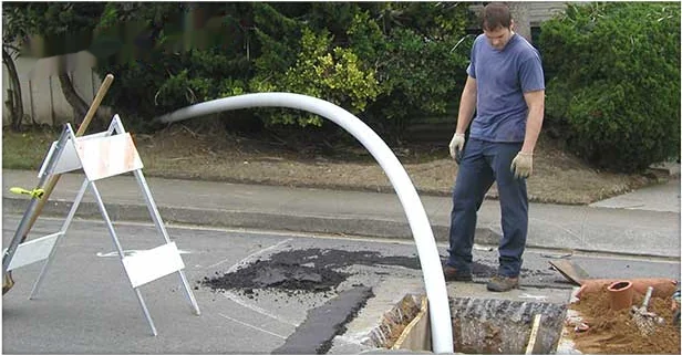 New sewer pipe staged at a street excavation during a line replacement